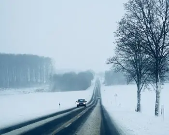 Hire car covered by excess insurance driving along a road between snowy fields