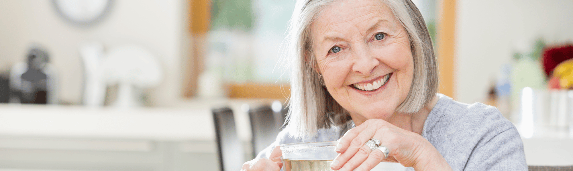 older lady smiling holding a cup of tea