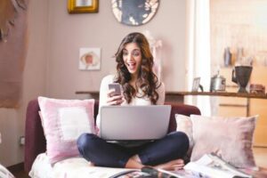 woman sitting with her laptop happy because she has saved money with moneymaxim